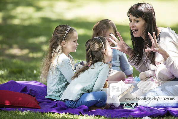 Mother telling stories to children on picnic blanket