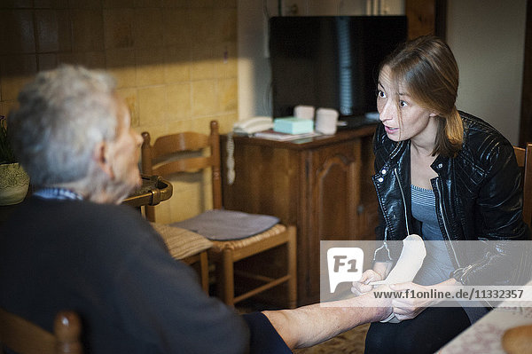 Reportage über eine selbstständige Krankenschwester in Haute-Savoie  Frankreich. Aline ist jeden Tag in ihrem kleinen Bergdorf unterwegs  um ihre Patienten zu besuchen. Sie hat auch eine Praxis in der Stadt  die sie sich mit zwei anderen Kollegen teilt. Aline hilft einer Patientin beim Anziehen ihrer Stützstrumpfhose.