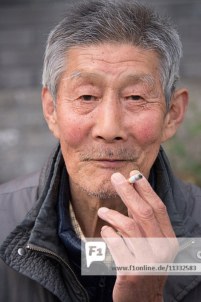 Asien China Peking  älterer Mann beim Rauchen