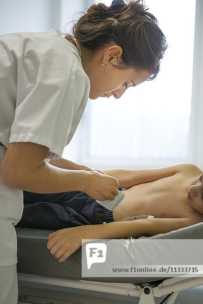 Reportage aus der pädiatrischen Notaufnahme eines Krankenhauses in Haute-Savoie  Frankreich. Eine Krankenschwester klebt einem Patienten ein Pflaster gegen Schmerzen auf  bevor sie eine Blutuntersuchung durchführt.