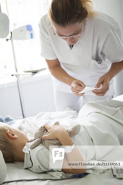 Reportage über die pädiatrische Abteilung eines Krankenhauses in Haute-Savoie  Frankreich. Eine Krankenschwester klebt einem jungen Patienten vor einer Blutuntersuchung ein Anästhesiepflaster auf.