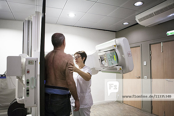 Reportage in einem Radiologiezentrum in Haute-Savoie  Frankreich. Ein Techniker positioniert einen Patienten für eine Röntgenaufnahme des Schlüsselbeins.