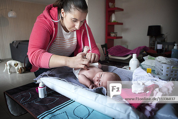 Reportage über eine unabhängige Hebamme bei Hausbesuchen nach der Geburt. Die Hebamme reinigt die Nabelschnur.