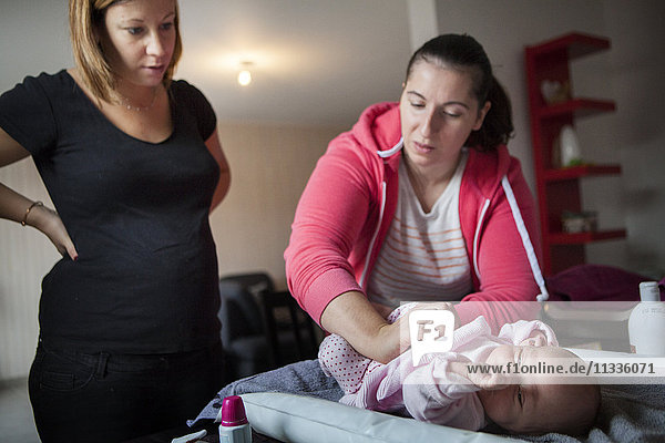 Reportage über eine freiberufliche Hebamme bei Hausbesuchen nach der Entbindung. Die Hebamme zeigt einer frischgebackenen Mutter  wie sie den Bauch ihres Babys massiert.
