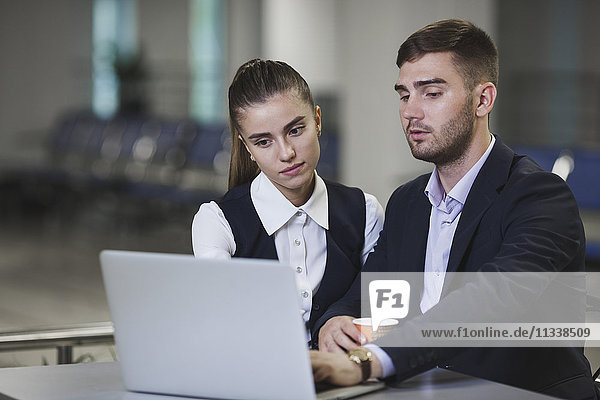 Junger Geschäftsmann und Geschäftsfrau mit Laptop am Tisch des Flughafens