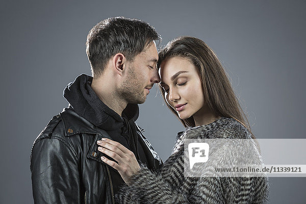Romantisches Paar in warmer Kleidung vor grauem Hintergrund