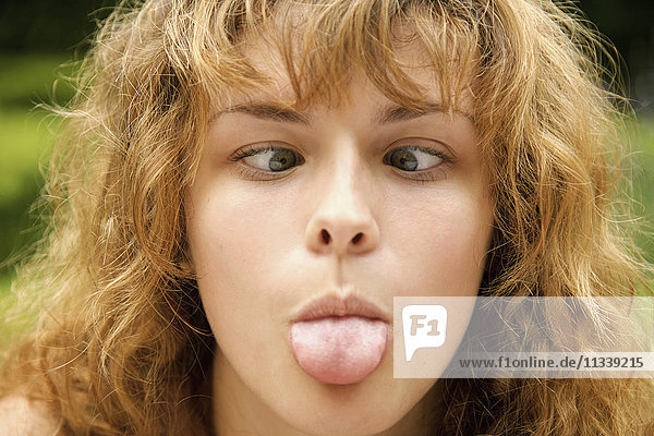 Close-up of cross-eyed woman sticking out tongue