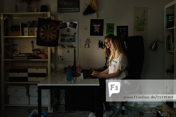 Teenager-Mädchen mit Computer am Tisch in der Dunkelkammer zu Hause