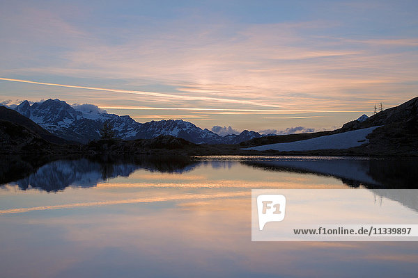 Snowy peaks reflected in Lake Zana at sunrise Malenco Valley Valtellina Province of Sondrio Lombardy Italy Europe