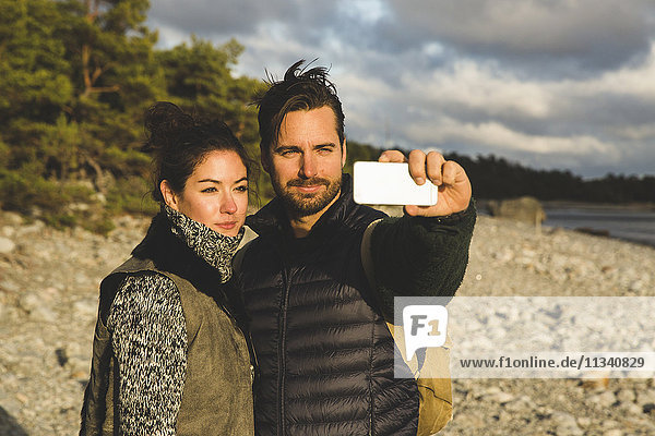 Couple taking selfie at beach during sunset