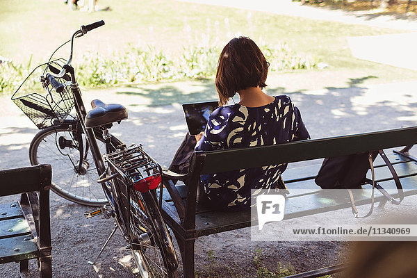 Hochwinkelansicht der Geschäftsfrau mit digitalem Tablett im Sitzen auf der Parkbank