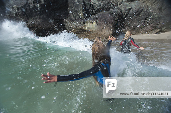 Mädchen springen in den Wellen von Kynance Cove  Cornwall  England  Vereinigtes Königreich  Europa