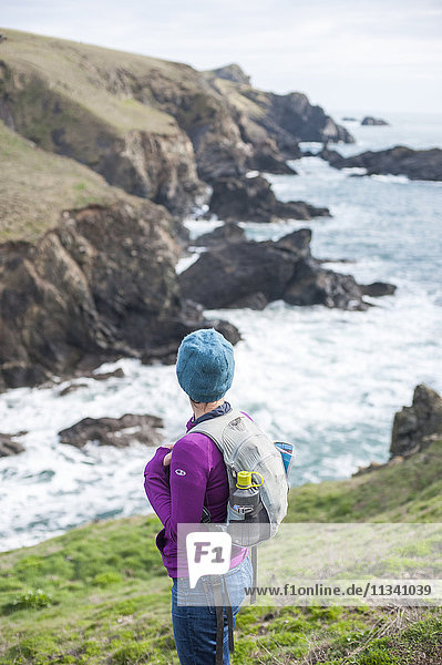 Eine Frau wandert auf dem Küstenweg an der Westseite der Lizard-Halbinsel  Cornwall  England  Vereinigtes Königreich  Europa
