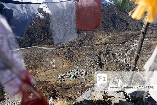 Blick auf die Kyanjin Gompa im Langtang-Tal  gesehen durch buddhistische Gebetsfahnen auf dem Gipfel des Kyanjin Ri  Langtang  Nepal  Himalaya  Asien