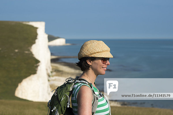 Eine Frau blickt auf die Klippen in der Nähe von Beachy Head mit Blick auf die Seven Sisters-Küste  South Downs National Park  East Sussex  England  Vereinigtes Königreich  Europa