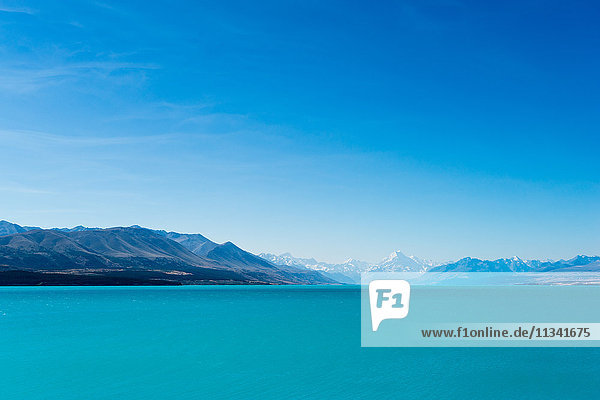 A turquoise blue lake with snow covered mountains in the distance  South Island  New Zealand  Pacific