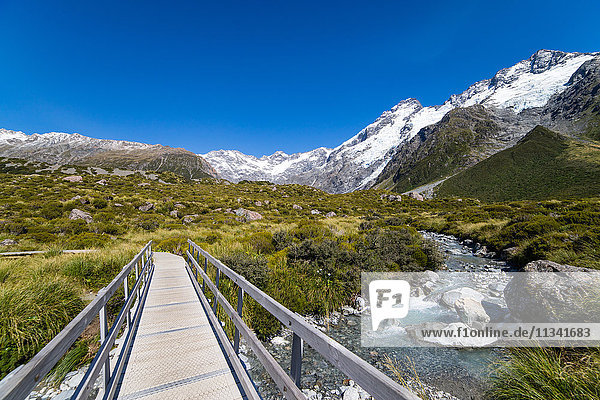 A hiking trail crosses wooden bridge over a creak high up in the mountains  South Island  New Zealand  Pacific