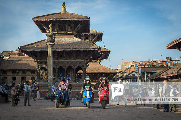 Eine Gruppe von Touristen sitzt auf ihren Motorrollern auf dem historischen Tempelplatz in Patan  Kathmandu  Nepal  Asien
