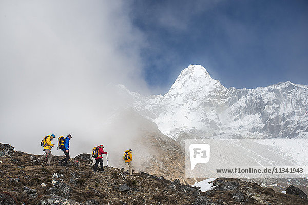 Ein Team von vier Bergsteigern macht sich auf den Weg zum Basislager der Ama Dablam  der 6856 m hohe Gipfel ist in der Ferne zu sehen  Khumbu-Region  Himalaya  Nepal  Asien