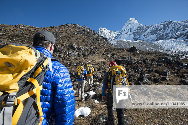 A team of four climbers make their way to Ama Dablam Base Camp  the 6856m peak seen in the distance  Khumbu Region  Himalayas  Nepal  Asia
