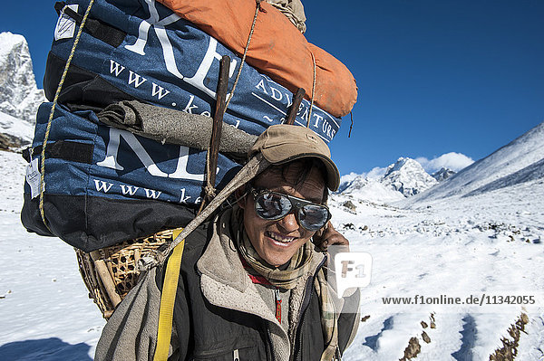Ein Sherpa in der Nähe von Dingboche  der die Ausrüstung für die Bergsteigerexpeditionen zum Everest-Basislager schleppt  macht eine kurze Pause  Region Khumbu  Nepal  Asien