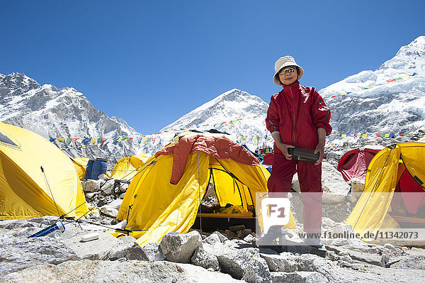 Eine Frau steht kurz nach der Besteigung des Everest neben ihrem Zelt  Khumbu-Region  Himalaya  Nepal  Asien