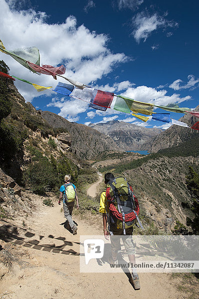 Gebetsfahnen markieren einen hohen Punkt des Weges  an dem die Wanderer mit einem ersten Blick auf den Phoksundo-See belohnt werden  Dolpa-Region  Himalaya  Nepal  Asien
