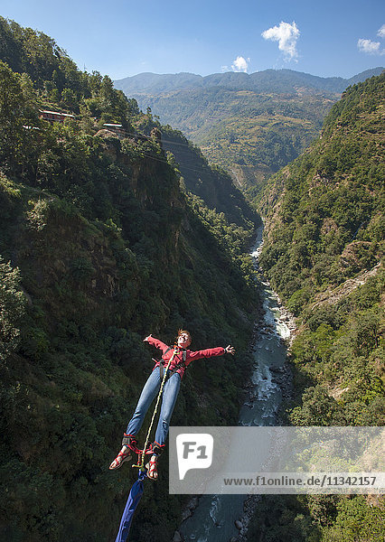 Ein Mädchen springt rückwärts von einem Bungy  Nepal  Asien