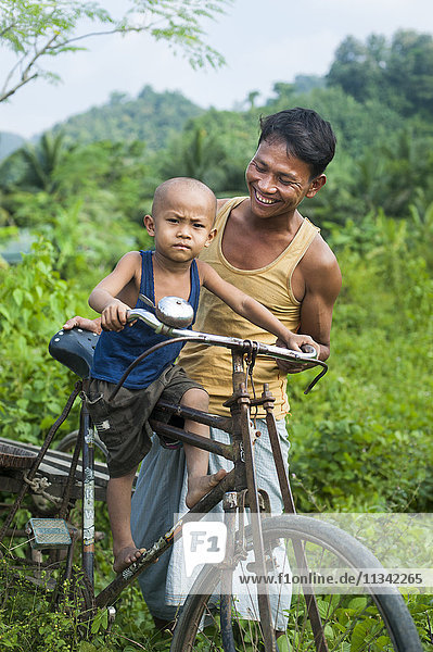 Ein Mann balanciert seinen kleinen Jungen auf seinem Fahrrad  Chittagong Hill Tracts  Bangladesch  Asien