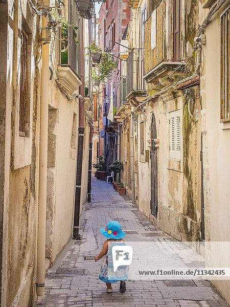 Little girl heading down a narrow Sicilian lane  Syracuse  Sicily  Italy  Europe