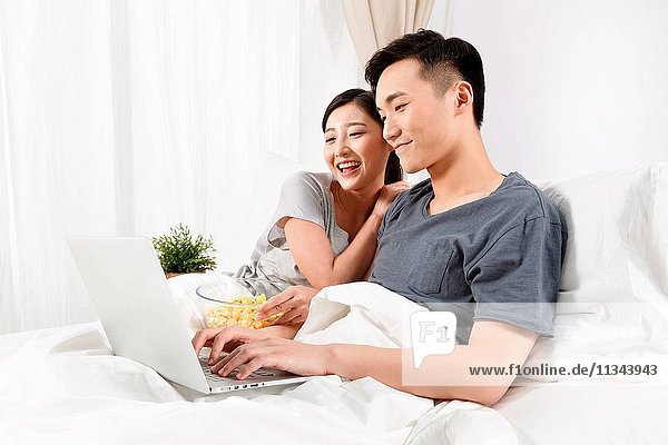 Young couple sitting on the bed to see the computer