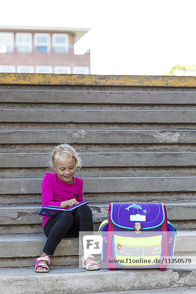 Blond girl sitting with school bag on stairs  Kiel  Schleswig-Holstein  Germany  Europe