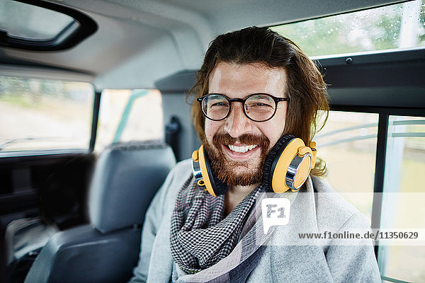 Happy bearded man in car wearing headphones