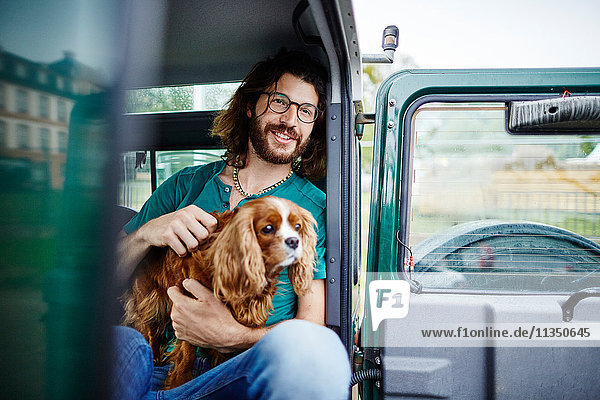 Man with dog sitting in off-road vehicle