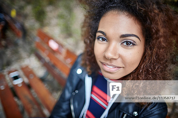 Portrait einer lächelnden jungen Frau auf einer Parkbank