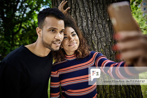 Smiling young couple on park bench taking a selfie