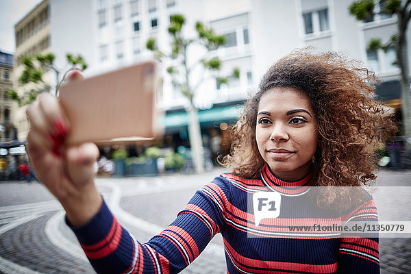 Junge Frau in der Stadt macht ein Selfie