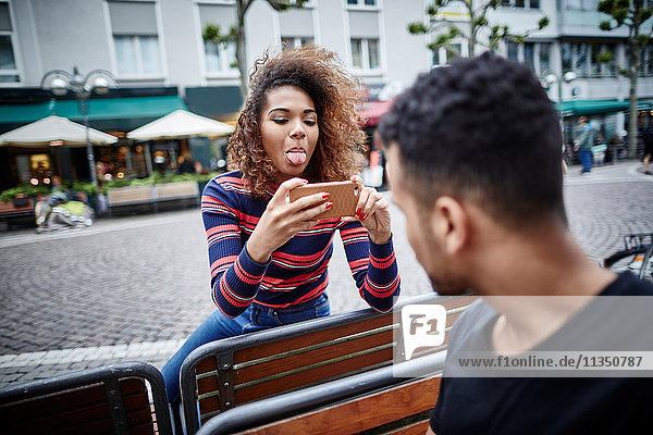 Playful young woman taking cell phone picture of her boyfriend
