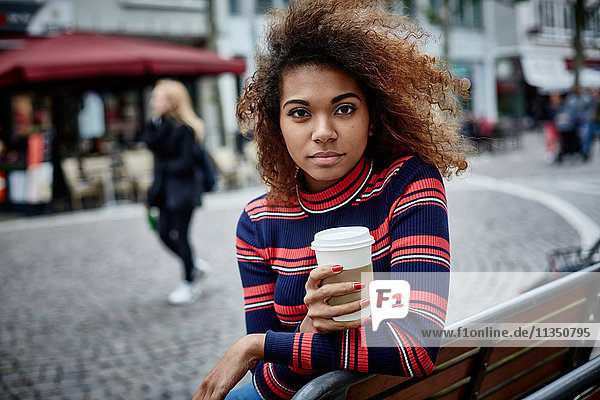 Portrait einer jungen Frau in der Stadt mit Coffee to go