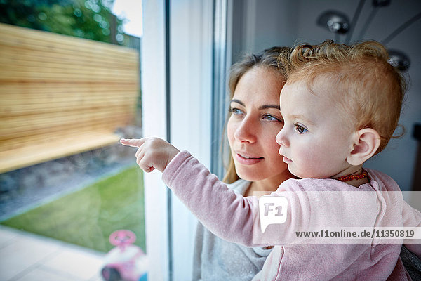 Mother and baby girl looking out of window