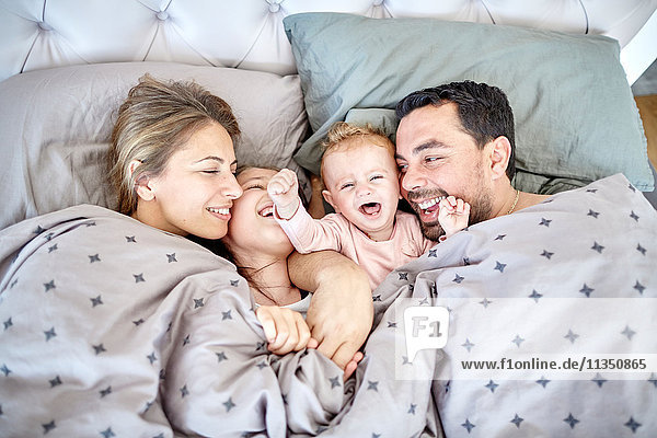 Happy family with baby in bed