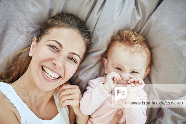 Portrait of happy mother and baby girl in bed