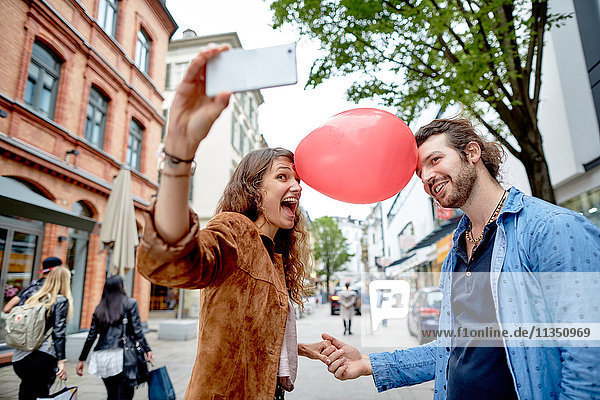 Verspieltes junges Paar macht ein Selfie in der Stadt