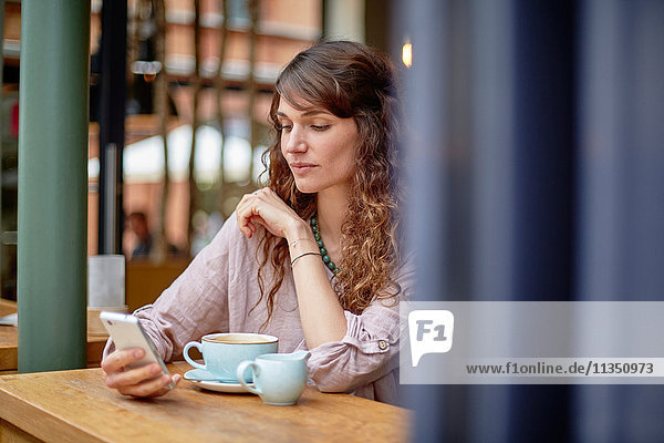 Young woman in a cafe looking at cell phone