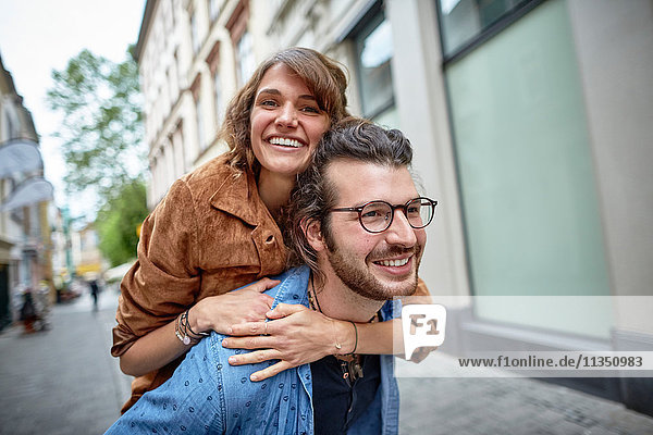 Junger Mann trägt seine Freundin huckepack in der Stadt