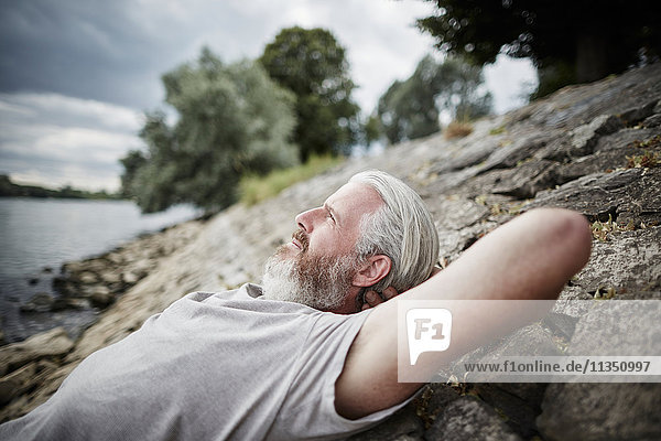 Relaxed bearded mature man at the riverside