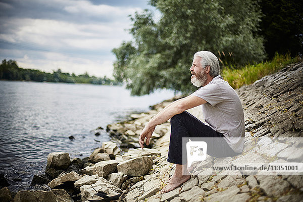 Bearded mature man sitting at the riverside