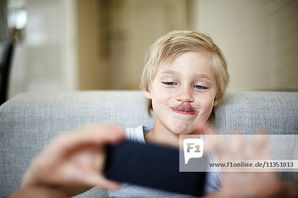 Junge mit Handy streckt seine Zunge heraus
