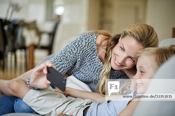 Fröhliche Mutter und Sohn schauen auf ein Handy