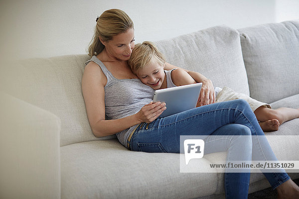Mother and son sitting on couch looking at tablet